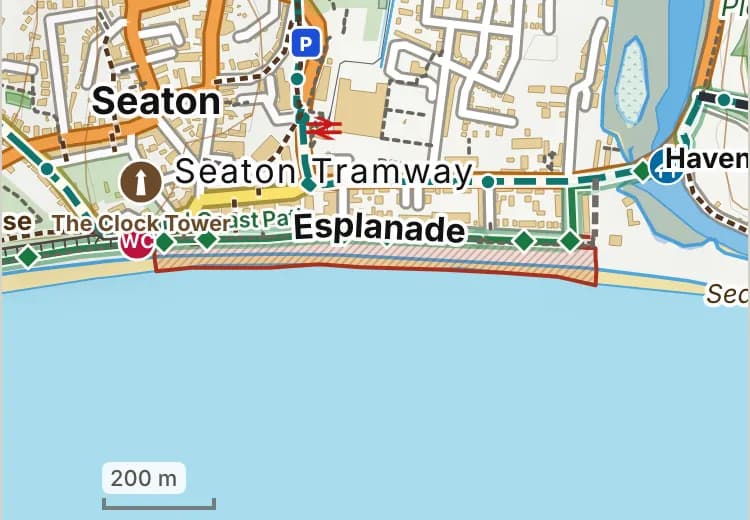 Map of Seaton beach: the stretch where dogs are banned 1 May to 30 September is hatched in brick, and the esplanade and west walk, where dogs must be on a lead all year, has a dashed brick edge.